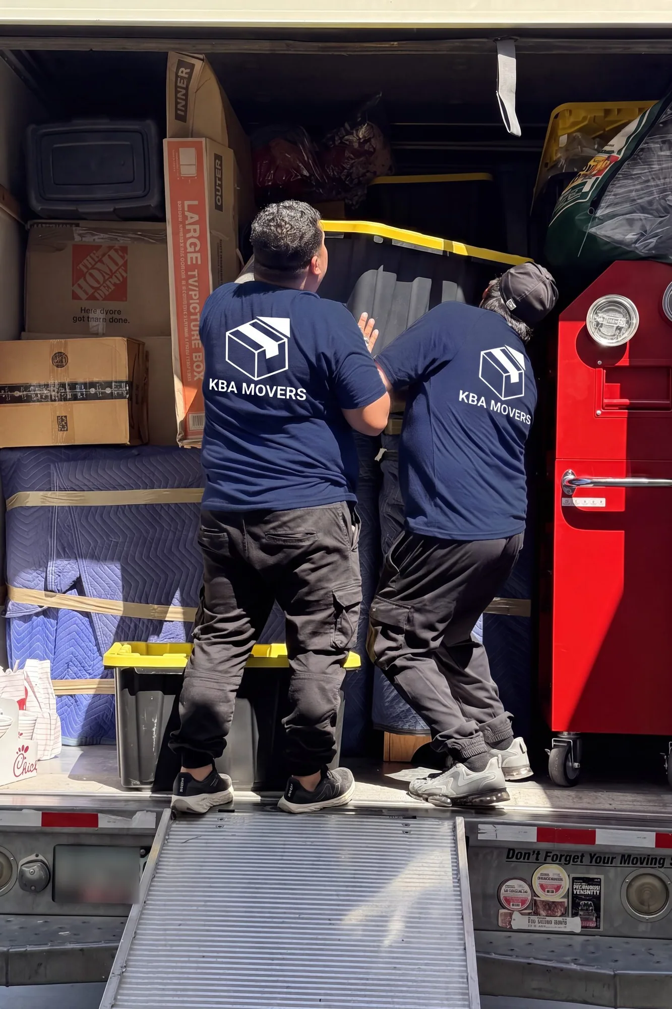 Movers loading wrapped office furniture into a truck